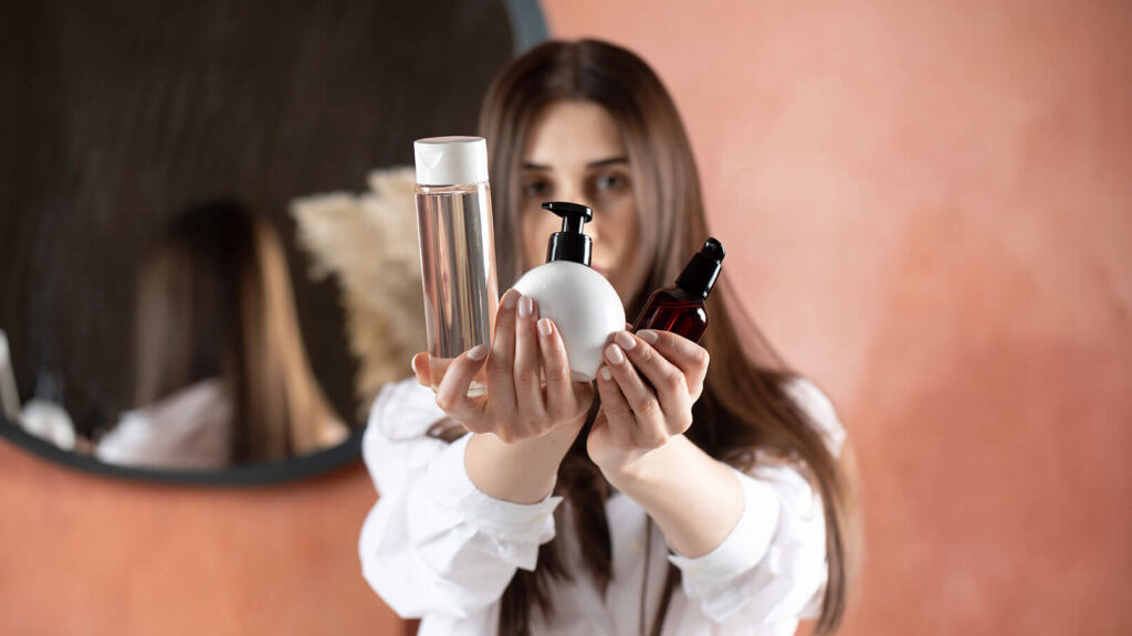 Mujer rodeada de muchos productos para el cabello sin saber cuál usar